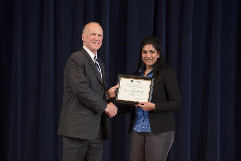 Doctor Potteiger posing for photo with an award recipient in a black blazer and a blue patterned top